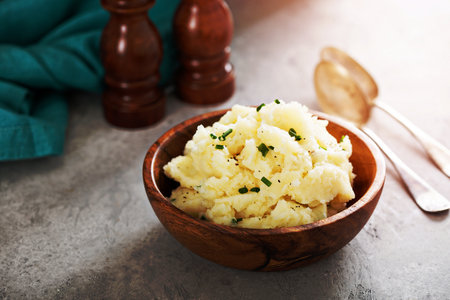 Fluffy mashed potatoes with chives in a wooden bowlの写真素材