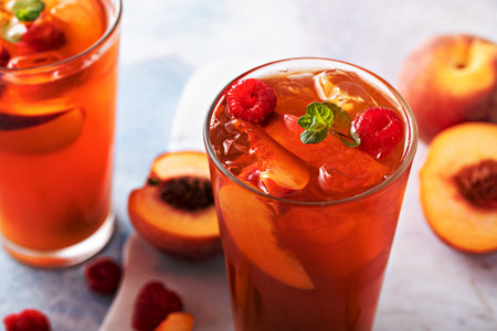Peach and raspberry iced tea or cocktail, cold and refreshing summer drinkの写真素材