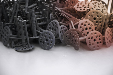 Background of many gray plastic dowels fastening for thermal insulation. A huge pile of plastic...