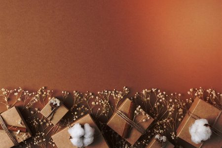Christmas decorations with gifts and flowers on brown background. Flat lay, copy space