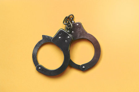 Bdsm sex games concept. Steel handcuffs lies on pastel beige background. Bondage and Discipline, Domination and Submission, Sadism and Masochismの写真素材