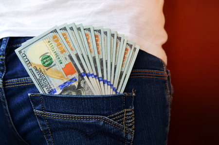 A large number of dollar bills lies in the back pocket of the girls jeans.の写真素材