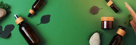 Cosmetic skin care products with eucalyptus and wood on green background. Flat lay, copy spaceの写真素材