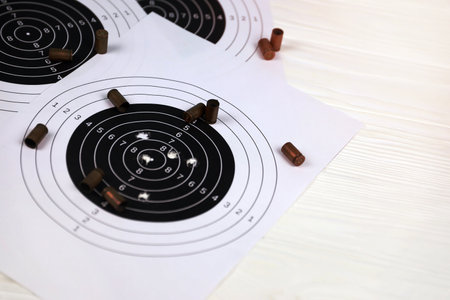 Many bullets with shooting targets on white table in shooting range polygon. Training for aiming and...