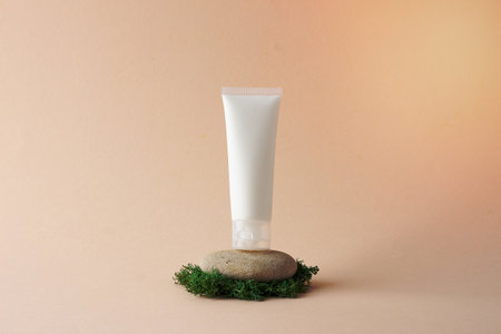 White tube of cosmetic cream on a stone podium with moss on beige background. Close up.の写真素材