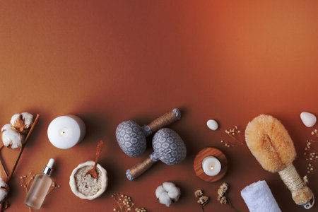 Spa treatment with cosmetic bottle, candles and herbal bag, towel on brown background. Flat lay, copy space.の写真素材