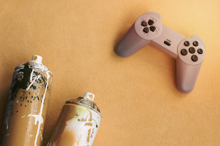 Teenagers and youth lifestyle concept. Joystick and two spray cans lies on the blanket of furry...
