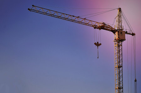 Abstract Industrial background with construction tower cranes over clear blue sky. Construction...