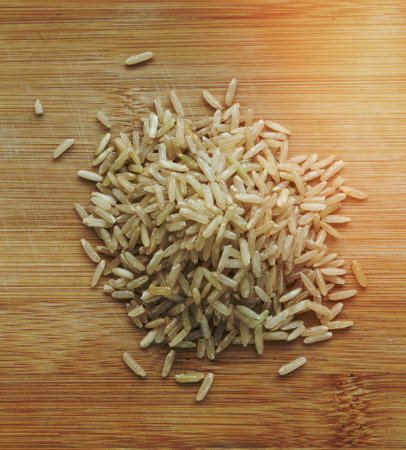 Whole grain rice uncooked long brown rice grain of rice laid on the floor of a rustic wooden table.の写真素材