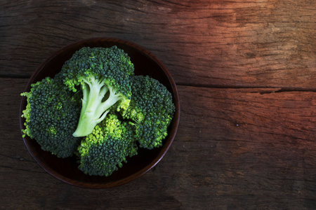 Fresh green broccoli in wood bowl over rustic wooden backgroundの写真素材
