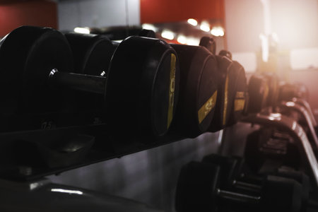 Row of black, heavy, metal dumbbells on stand in gym. Sport equipment for training.