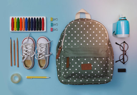 Creative flatlay of education blue table with backpack, shoes, colorful crayon, eye glasses, isolated on blue background, Concept of education and back to schoolの写真素材