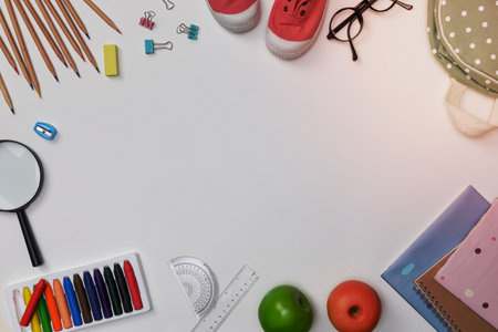 Creative flatlay of education white table with backpack, student books, shoes, colorful crayon, eye glasses, empty space isolated on white background, Concept of education and back to schoolの写真素材
