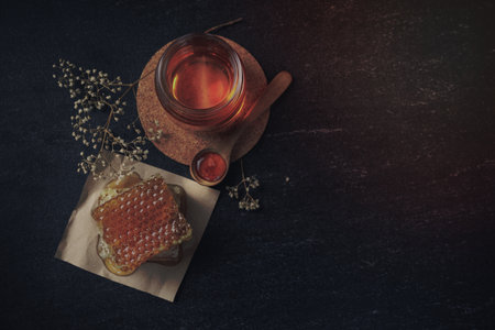 Honey bee and Honeycomb with honey dipper and dry flower on black background, bee products by organic natural ingredients conceptの写真素材