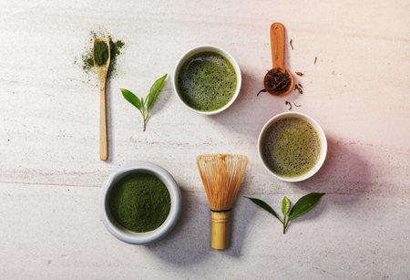 Organic matcha green tea powder in bowl with wire whisk and green tea leaf on white stone table, Organic product from the nature for healthy with traditional styleの写真素材