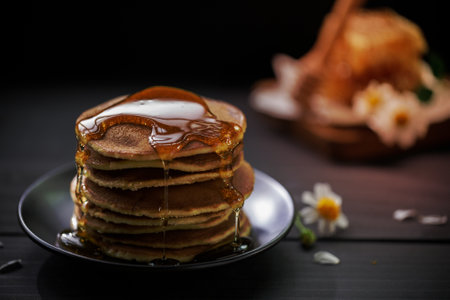 Honey dripping on the stack of pancakes for breakfast on the wooden table, healthy products by organic natural ingredients conceptの写真素材