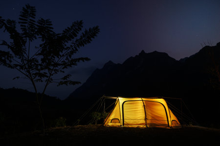 Glowing yellow tent in the mountains with cloud in natural park, Tourism conceptの写真素材