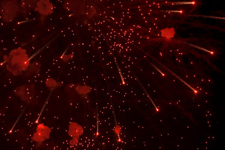 Salute. Bright, red splashes of fireworks in the dark sky. Night fireworks.