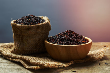Rice berry or uncooked brown rice in bowl and burlap sack on wooden tableの写真素材
