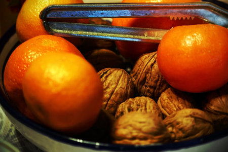 Mandarins and whole walnuts in a bowl with vintage metal nutcrackerの写真素材