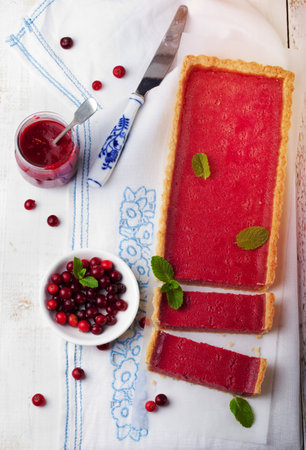 Cranberry, bilberry custard tart, pie,cake with fresh berries and mint leaves on a white wooden backgroundの写真素材