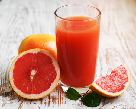 Grapefruit juice and ripe grapefruits on a wooden backgroundの写真素材