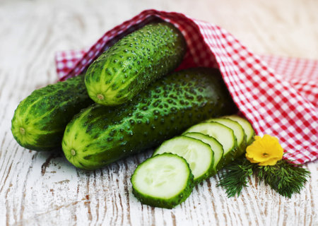 Green cucumbers and slices on a wooden backgroundの写真素材