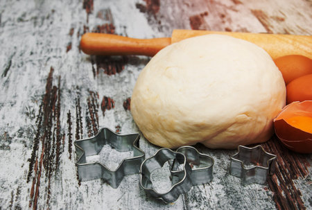 Baking ingredients - eggs, dough, and cutter on a wooden background