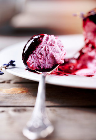 Berry ice cream with lavendr flowers on a white plate on a wooden backgroundの写真素材