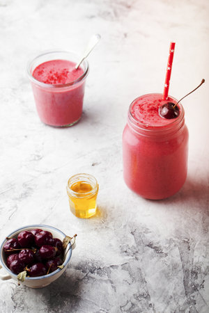 Cherry coconut milk, yogurt and honey smoothie on a stone backgroundの写真素材