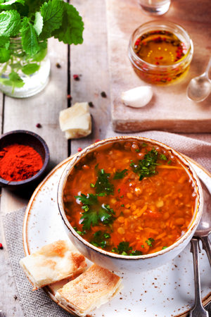 Lentil soup with smoked paprika and bread in a ceramic bowl on a wooden backgroundの写真素材