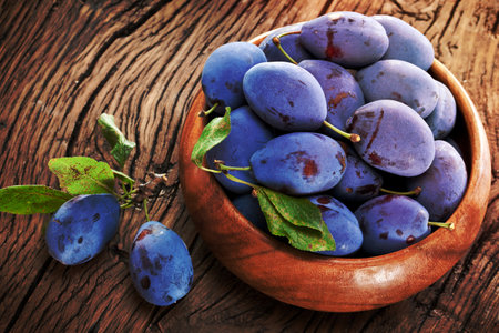 Plums on an old wooden table in the garden.の写真素材