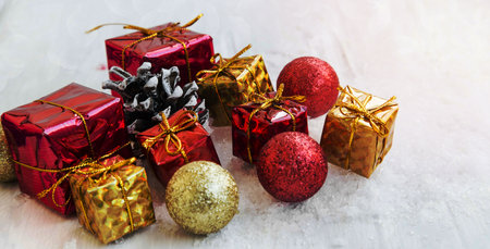 Festive Red and Golden Christmas Presents and Balls with Glitter in the Snowの写真素材
