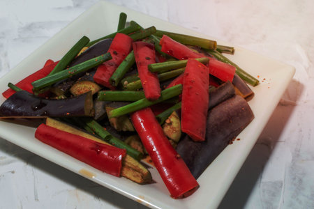 Fried eggplant has chili pepper and green onion in plate on white background close up, top view, healthy food concept.の写真素材
