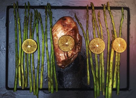 Chicken grill with lemon and asparagus in black tray top view, close up, healthy food concept.の写真素材