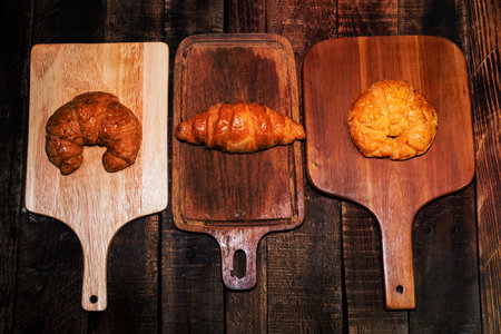 Croissant isolated in cutting board on wood background closeup, top view, copy space, breakfast food...