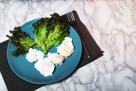 Egg poached has lettuce in plate on marble table background top view, close up, breakfast food concept.の写真素材