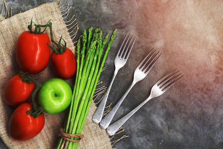 Fresh vegetable on stone background has asparagus tomato apple fork copy space, top view, healthy food concept.の写真素材