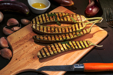 Grilled eggplants in cutting board has fork and olive oil  garlic isolated on wood background close up, top view, healthy food concept.の写真素材