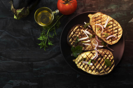 Grilled eggplants in plate has fork on isolated on black wood background close up, top view, healthy food concept.の写真素材
