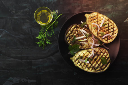 Grilled eggplants in plate has fork on isolated on black wood background close up, top view, healthy food concept.の写真素材