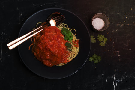 Pasta spaghetti with tomato sauce in black plate on chalkboard, top view, Italian food concept.の写真素材