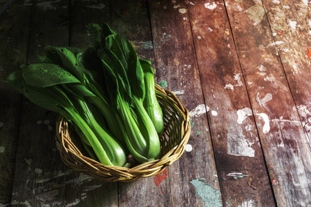 Bok choy vegetable in basket on wood background close up, top view, healthy food concept.の写真素材