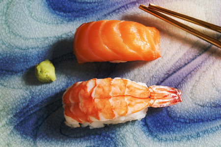 Salmon and prawn sushi on plate has chopstick close up, top view, Japanese food concept.の写真素材