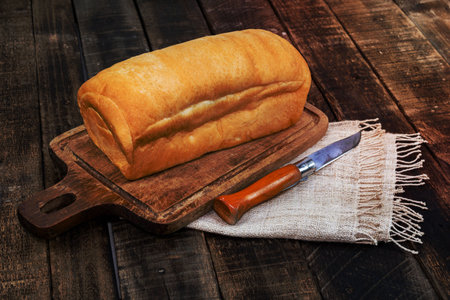 loaf bread isolated on wood background have cutting board knife, gold rustic crusty bun, top view,...