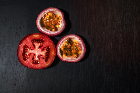 Tomato slice has passion fruit on black wood background top view, healthy food concept.の写真素材