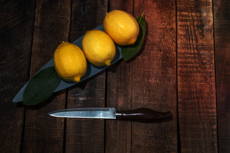 Lemon pile in bowl has leaves on wood background close up, top view, bio food concept.の写真素材