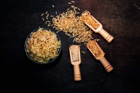 rice brown in bowl have grain in spoon isolated on black wood table background close up, top view, food and drink concept.の写真素材