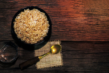 rice brown in black bowl have spoon isolated on wood table background close up, top view, food and drink concept.の写真素材