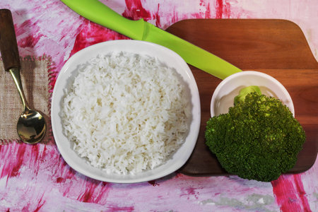Rice in bowl and vegetable have spoon chopping board knife isolated on red background  close up, top view, food and drink concept.の写真素材